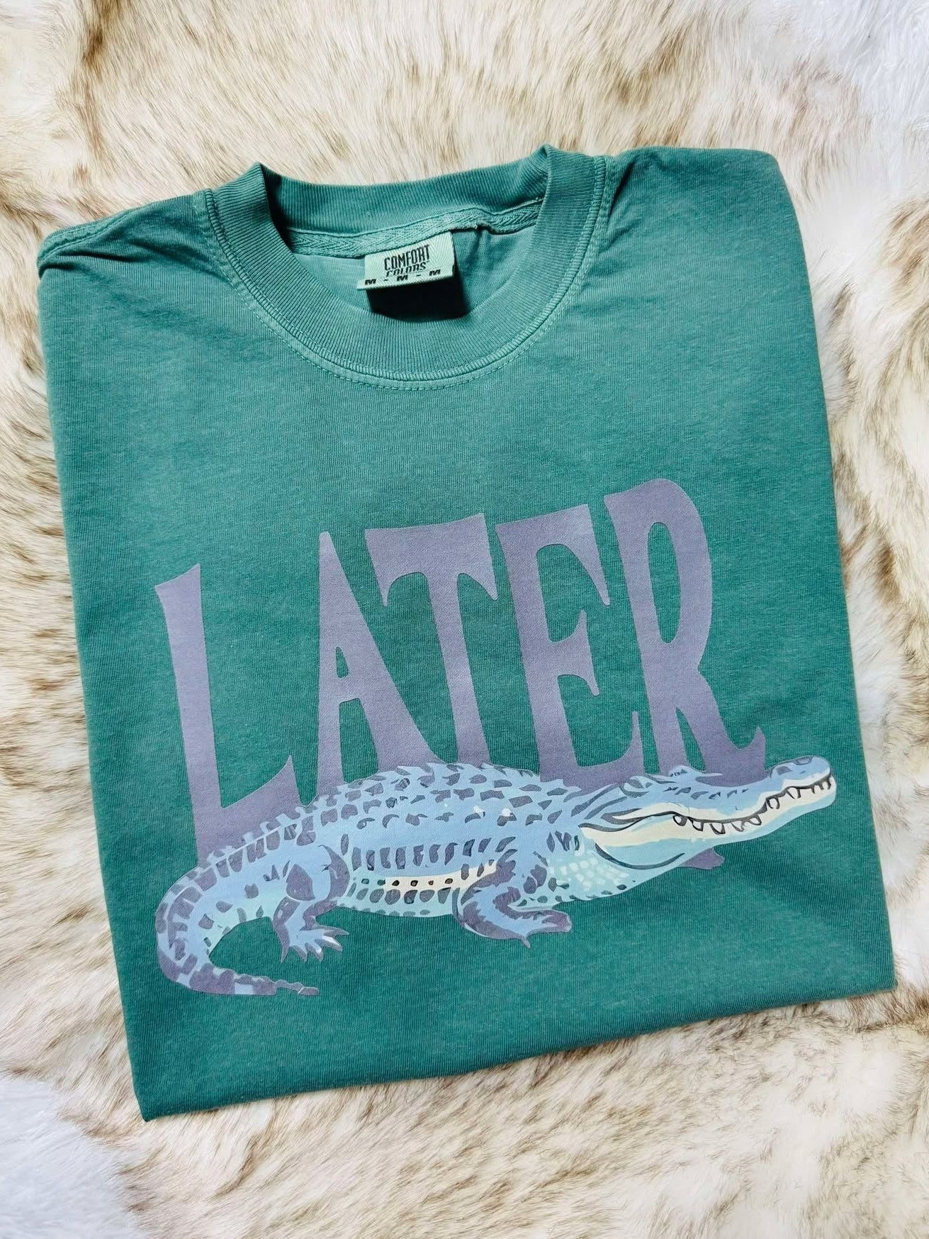 Green t-shirt with purple alligator graphic and 'LATER' gator text on a fur surface Alligator