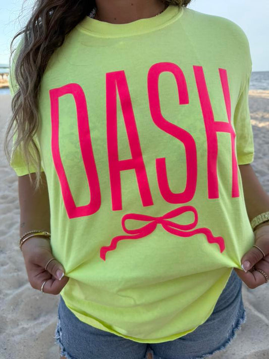 Person wearing a bright yellow t-shirt with 'DASH' printed in pink on a beach.